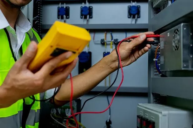 engineer inspecting a switchgear cabinet for faults to show importance of electrical testing.